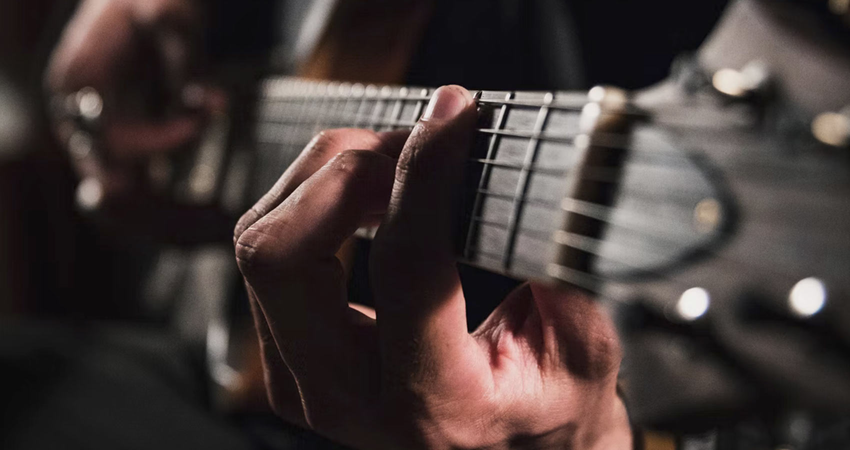 Nahaufnahme einer Hand, welche eine Gitarre hält.